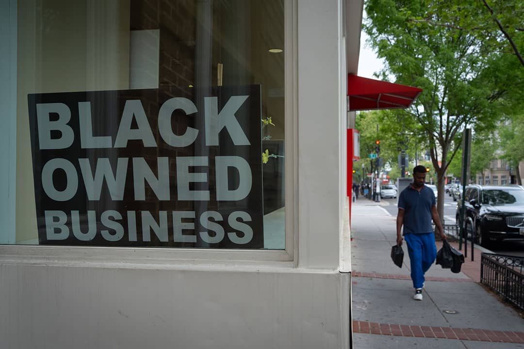 A Black Owned Business sign hangs in the window of a corner shop.